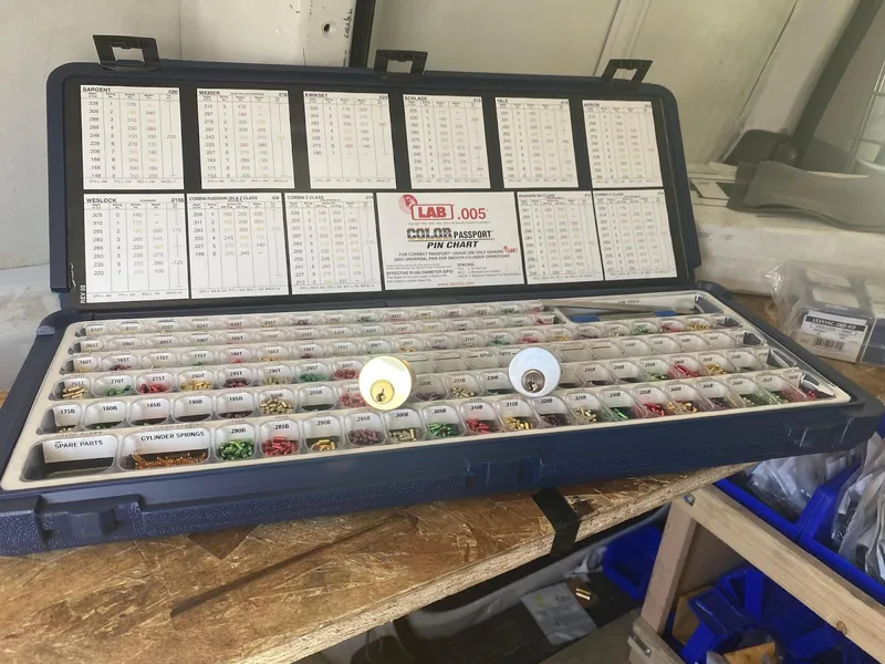Locksmith rekeying pin kit with color-coded pins and two lock cylinders on a workbench
